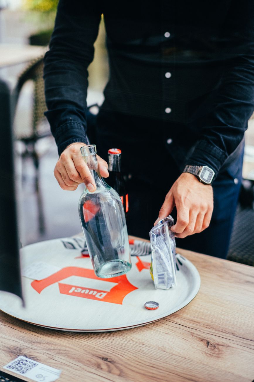 man taking glass bottle from tray