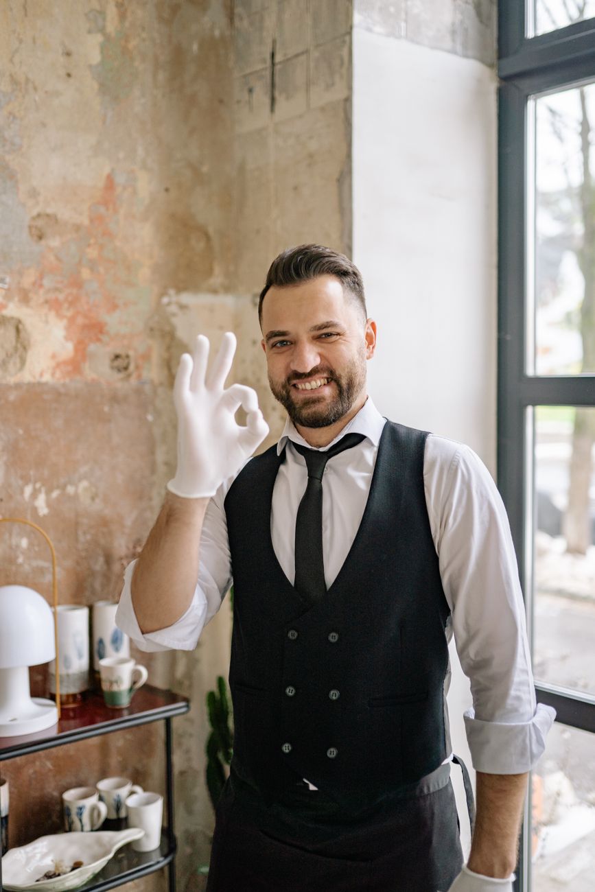 man in black vest and white gloves smiling