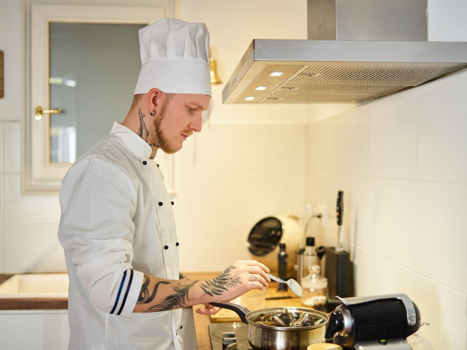 man in white chef uniform holding stainless spoon