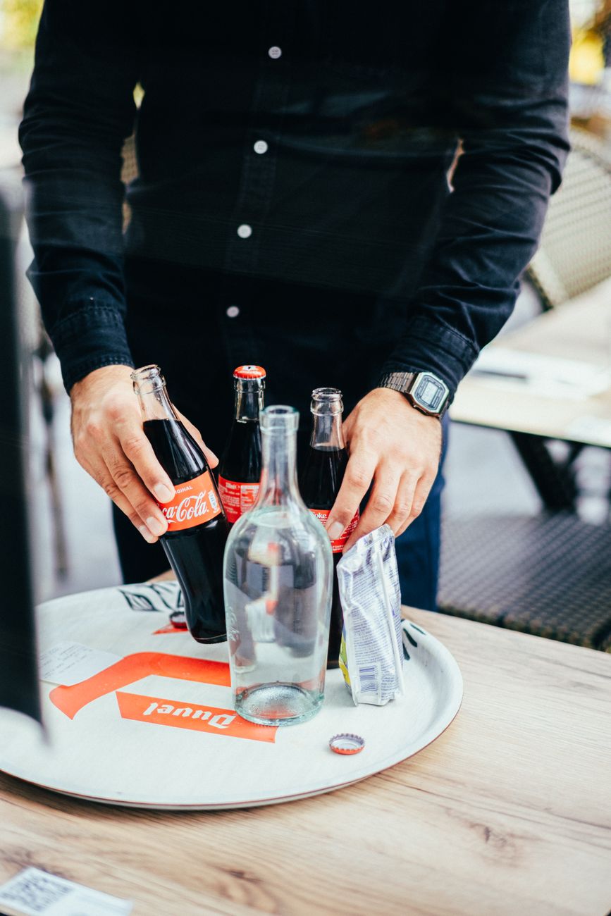 view on man putting cola bottles on tray