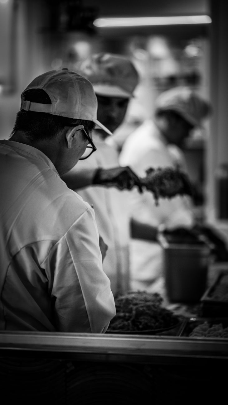 black and white photography of people working in a kitchen
